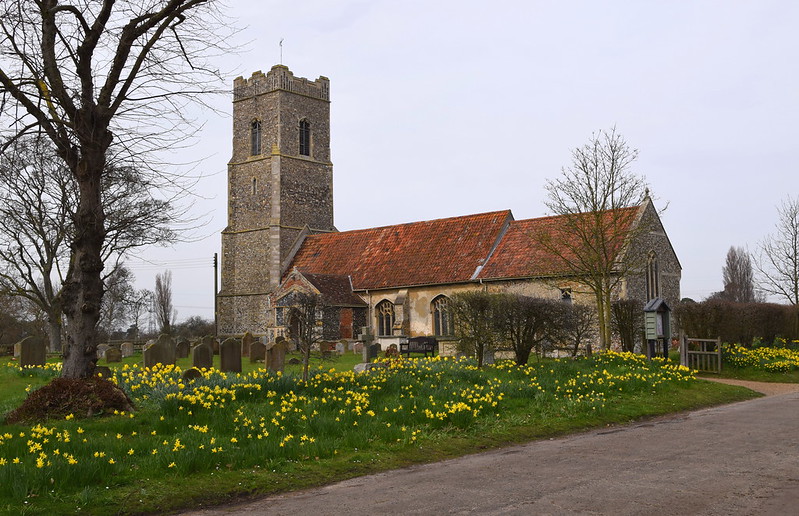 Snape Church showing the daffodils by the car-park